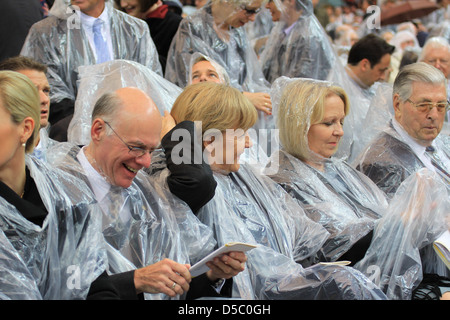 Norbert Lammert Bettina Wulff Angela Merkel celebrating the Mass of Pope Benedict XVI at olympic stadium wearing rain coats. Stock Photo