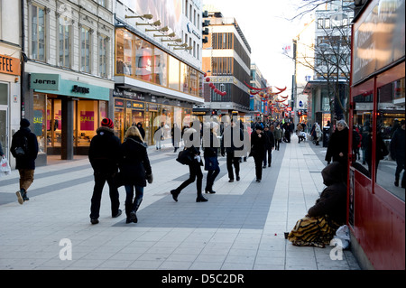 A beggar sits in the cold winter on one of the main shopping streets in Stockholm, Sweden. Stock Photo