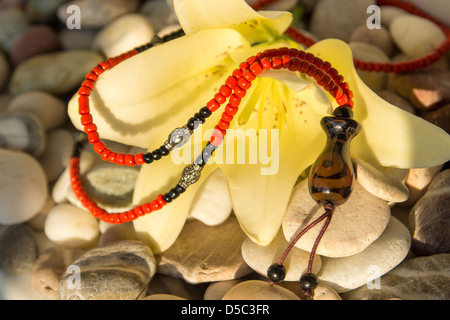 handmade jewelry with yellow lily on sea pebbles, sunlight Stock