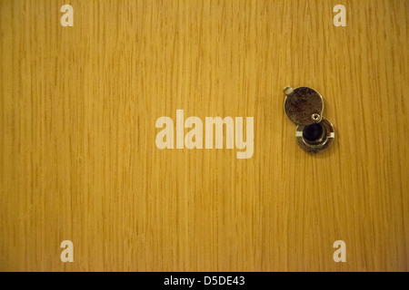 A photograph of a peephole on a wooden door. Stock Photo