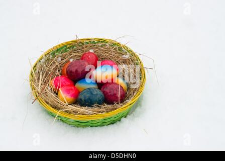 ILLUSTRATION - An illustrated picture shows a basket filled with coloured Easter eggs standing in the snow in Sieversdorf, Germany, 29 March 2013. Photo: Patrick Pleul Stock Photo