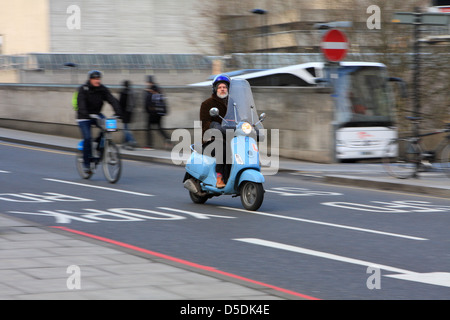 A motorcyclist and cyclist riding along a road near Waterloo in London, England. Stock Photo