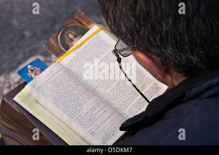 Jerusalem, Israel. 29th March 2013.  A man reads from the bible as he awaits the opening of the doors to the Church of The Holy Sepulchre on Good Friday. Jerusalem, Israel. 29-Mar-2013.  Thousands of Christian pilgrims retraced the last steps of Jesus through the Via Dolorosa to the Church of the Holy Sepulchre on Good Friday, singing and chanting in a mix of languages, costumes and traditions. Credit: Nir Alon / Alamy Live News Stock Photo