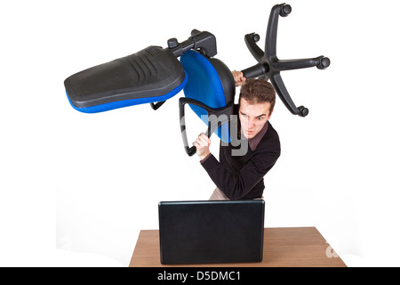 young angry man standing above a laptop with an office chair preparing to destroy it Stock Photo