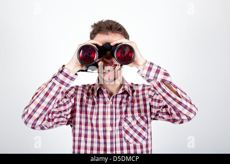 young man looking with binoculars at you Stock Photo