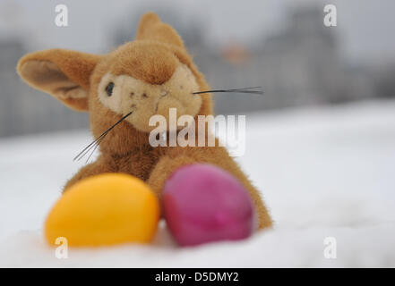 ILLUSTRATION - An Easter bunny cuddle toy and two coloured Easter eggs lie in the snow in front of the Reichstag in Berlin, Germany, 29 March 2013. Searching for Easter eggs is somewhat cumbersome: according to region, either 'wet' or 'white'. Photo: Paul Zinken Stock Photo