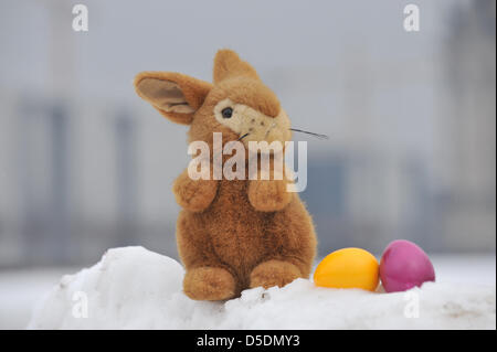 ILLUSTRATION - An Easter bunny cuddle toy and two coloured Easter eggs lie in the snow in front of the Reichstag in Berlin, Germany, 29 March 2013. Searching for Easter eggs is somewhat cumbersome: according to region, either 'wet' or 'white'. Photo: Paul Zinken Stock Photo