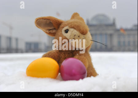 ILLUSTRATION - An Easter bunny cuddle toy and two coloured Easter eggs lie in the snow in front of the Reichstag in Berlin, Germany, 29 March 2013. Searching for Easter eggs is somewhat cumbersome: according to region, either 'wet' or 'white'. Photo: Paul Zinken Stock Photo