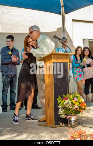 The principal of a Southern California continuation high school. congratulates a casually dressed female student at graduation. Stock Photo