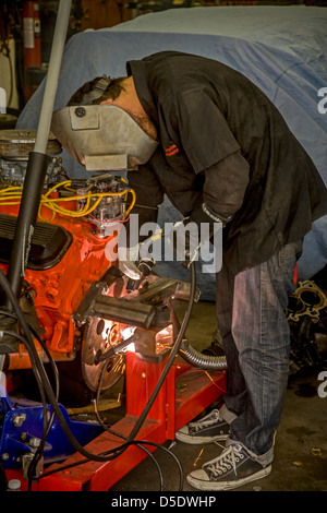 A teen boy arc welds an engine support in a high school auto shop class in San Clemente, CA, Stock Photo