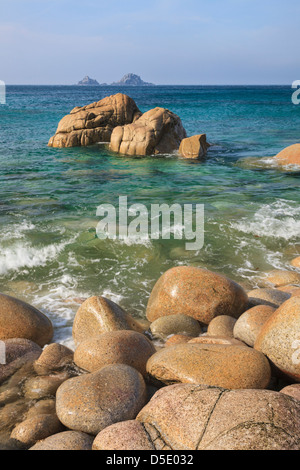 Boulders on Porth Nanven cove with Bubble Gum Rock and The Brisons in the distance. Stock Photo