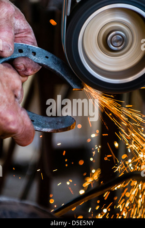 Sparks flying while a farrier is grinding a horeshoe in preparation for shoeing a horse. Brentwood, California, USA. Stock Photo