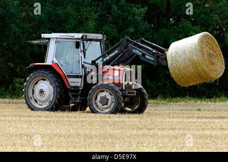 Farmer lifting a bale of straw with tractor, UK Stock Photo