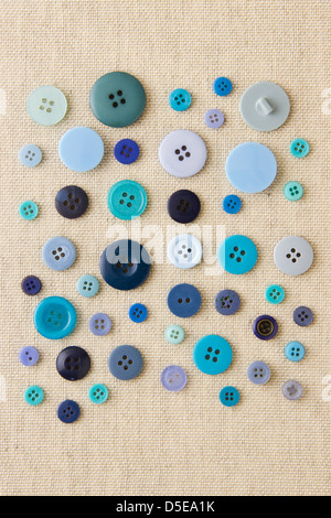 Many blue sewing or clothing buttons on hessian Stock Photo