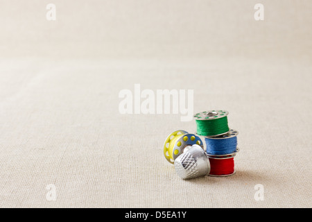 Sewing machine bobbins on hessian with thimble Stock Photo
