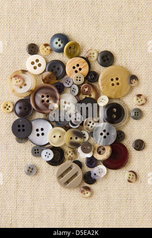 Many neutral brown sewing or clothing buttons on hessian Stock Photo