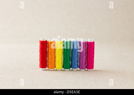 Spools or bobbins of thread, brightly coloured, arranged in rainbow colour formation Stock Photo