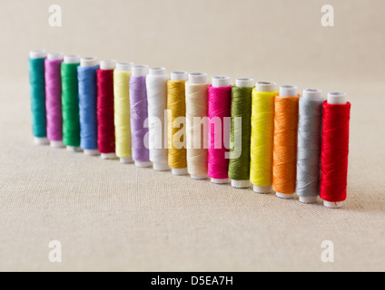 Spools and bobbins of thread, brightly coloured, arranged in a row Stock Photo