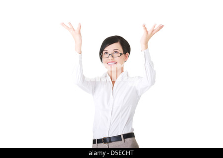 Smiling young woman is holding something abstract above her head. Happy girl with raised hands. Isolated on white background.  Stock Photo