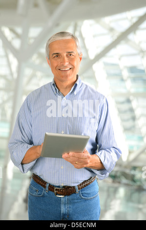 Closeup of a casual businessman in a modern factory holding a tablet computer. Vertical Format. Stock Photo