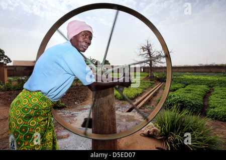 old woman pumps water from a well, Burkina Faso, Africa Stock Photo