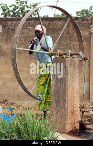 old woman pumps water from a well, Burkina Faso, Africa Stock Photo