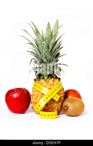 Fruits (pineapple, apple, kiwi and orange) isolated on white with a yellow measuring tape Stock Photo