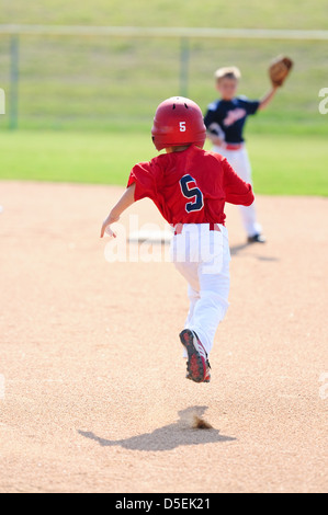 Little league boy running to second base. Stock Photo