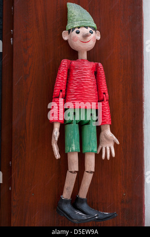 pinocchio puppet hanging on strings in front of wooden door Stock Photo