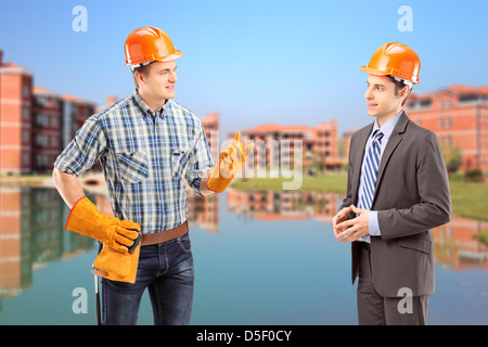 A male manual worker having a conversation with architect, construction site in the background Stock Photo