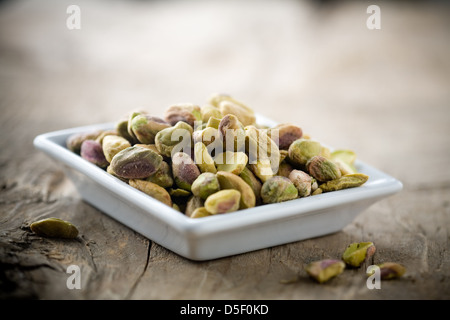 Small bowl of pistachios on wooden table Stock Photo