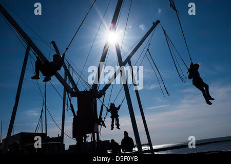 Aberystwyth Wales UK, Easter Sunday, 31 March 2013. Children enjoying the spring sunshine, playing on the bunjee trampolines on Aberystwyth promenade. The persistent easterly winds means that this has been the coldest March since 1962, and temperatures are set to be below average for the first week in April   photo ©keith morris Stock Photo