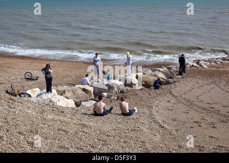 Young people sitting on the beach at Hastings Stock Photo