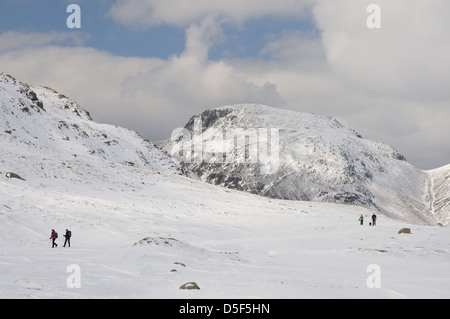 Walkers in winter next to Sprinkling Tarn, with Great Gable in the background, English Lake District Stock Photo