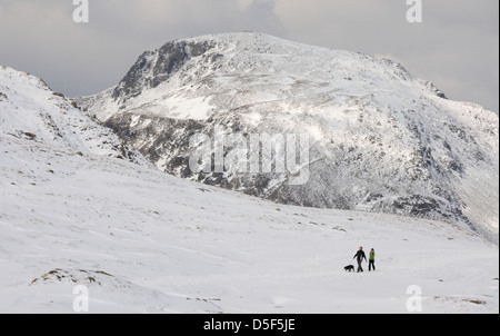 Walkers next to Sprinkling Tarn in winter in the English Lake District, with Great Gable in the background Stock Photo