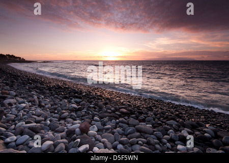 The sunset over a rocky beach in the tourist resort of Las Americas on the Canary island of Tenerife Spain Stock Photo