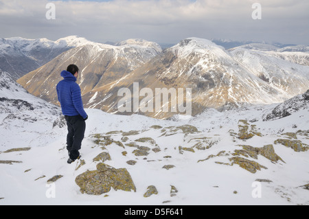 Walker on Long Pike, Great End, admiring the view towards Great Gable in winter in the English Lake District Stock Photo