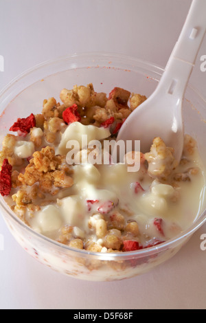 spoon in tub of Rumblers Oat clusters with strawberries & natural low fat probiotic yogurt set on white background - yoghurt Stock Photo