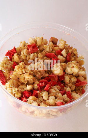 topping on tub of Rumblers Oat clusters with strawberries & natural low fat probiotic yogurt set on white background - yoghurt Stock Photo