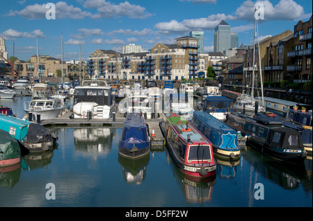 Narrow boats moored in Limehouse Basin with residential apartments and Canary Wharf in the background, London, UK Stock Photo