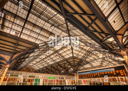 Intricate cast iron glazed Victorian engineering and detail of roof at Liverpool street station with concourse beneath Stock Photo