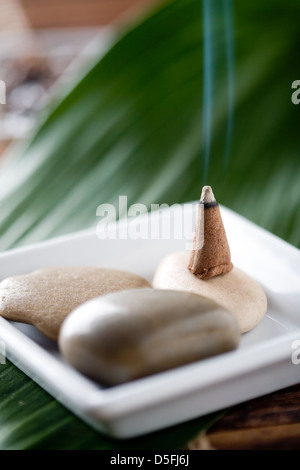 Brown incense stick burning on brown stones Stock Photo