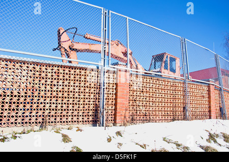 industrial place fence and old excavator machine in winter Stock Photo