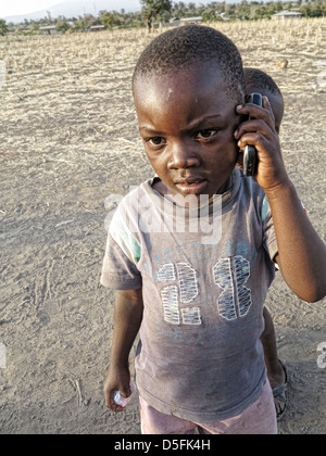 Africa;Happy small one year old Child using cell phone;Orphans; in School and at play outside in Moshi;Tanzania;East Africa Stock Photo