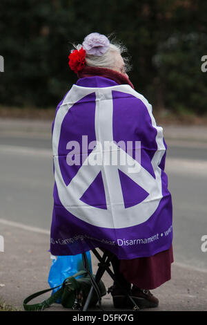 Aldermaston, UK. 1st April 2013.  Woman draped in CND flag outside an entrance to Aldermaston. Campaign for Nuclear Disarmament (CND) protest the Atomic Weapons Establishment (AWE) site at Aldermaston, Berkshire. CND aim to highlight their opposition to Britain's Trident nuclear weapons system and plans to replace it. Credit: Martyn Wheatley/Alamy Live News Stock Photo