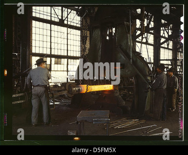A 1940s image showing workers using a steam drop hammer in the blacksmith shop of the Santa Fe Railroad in Albuquerque, New Mexico. This photograph highlights labor in railroad construction and maintenance. Stock Photo