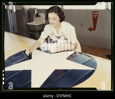 Painting the American insignia on airplane wings is a job that Mrs. Irma Lee McElroy, a former office worker, does with precision and patriotic zeal. Mrs. McElroy is a civil service employee at the naval Air Base, Corpus Christi, Texas. Her husband is a f Stock Photo