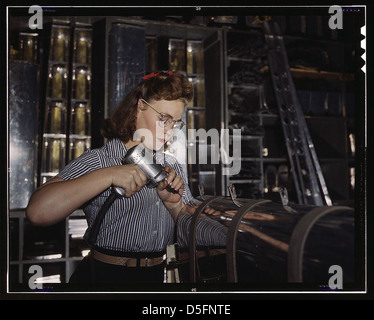 Operating a hand drill at the North American Aviation, Inc., [a] woman is in the control surface department assembling a section of the leading edge for the horizontal stabilizer of a plane (LOC)