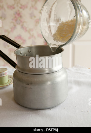 Pouring wax flakes into into bain marie. Tea cup candle making step-by-step 2 Stock Photo