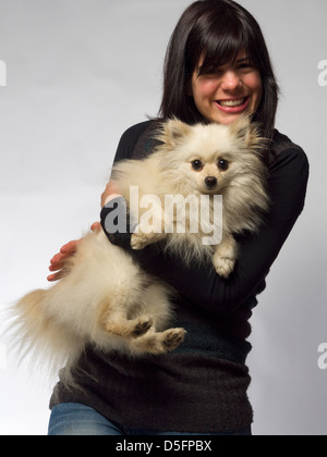 Woman holding small white pomeranian dog Stock Photo